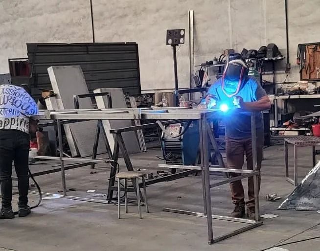 Un hombre está soldando una pieza de metal en una fábrica.