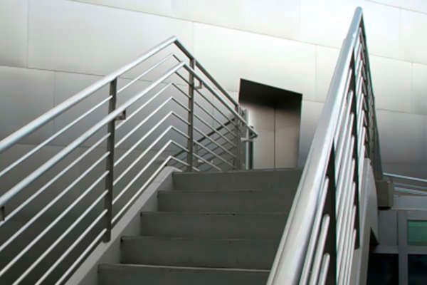Un conjunto de escaleras con barandilla de metal que conducen a un ascensor.