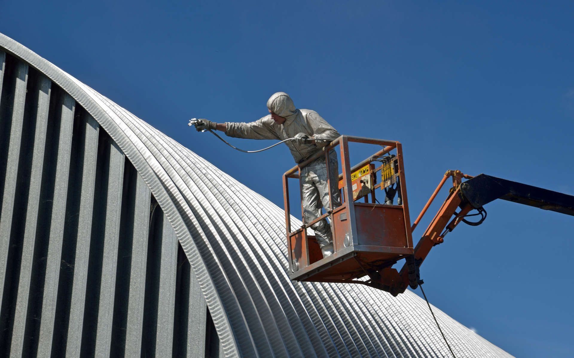 Un hombre está pintando el techo de un edificio en un ascensor.