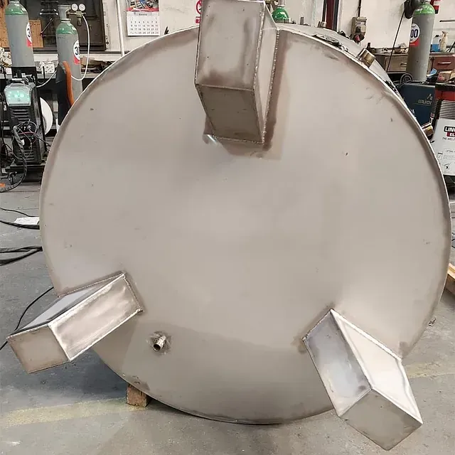 Un gran tanque de acero inoxidable se encuentra en el suelo en una fábrica.