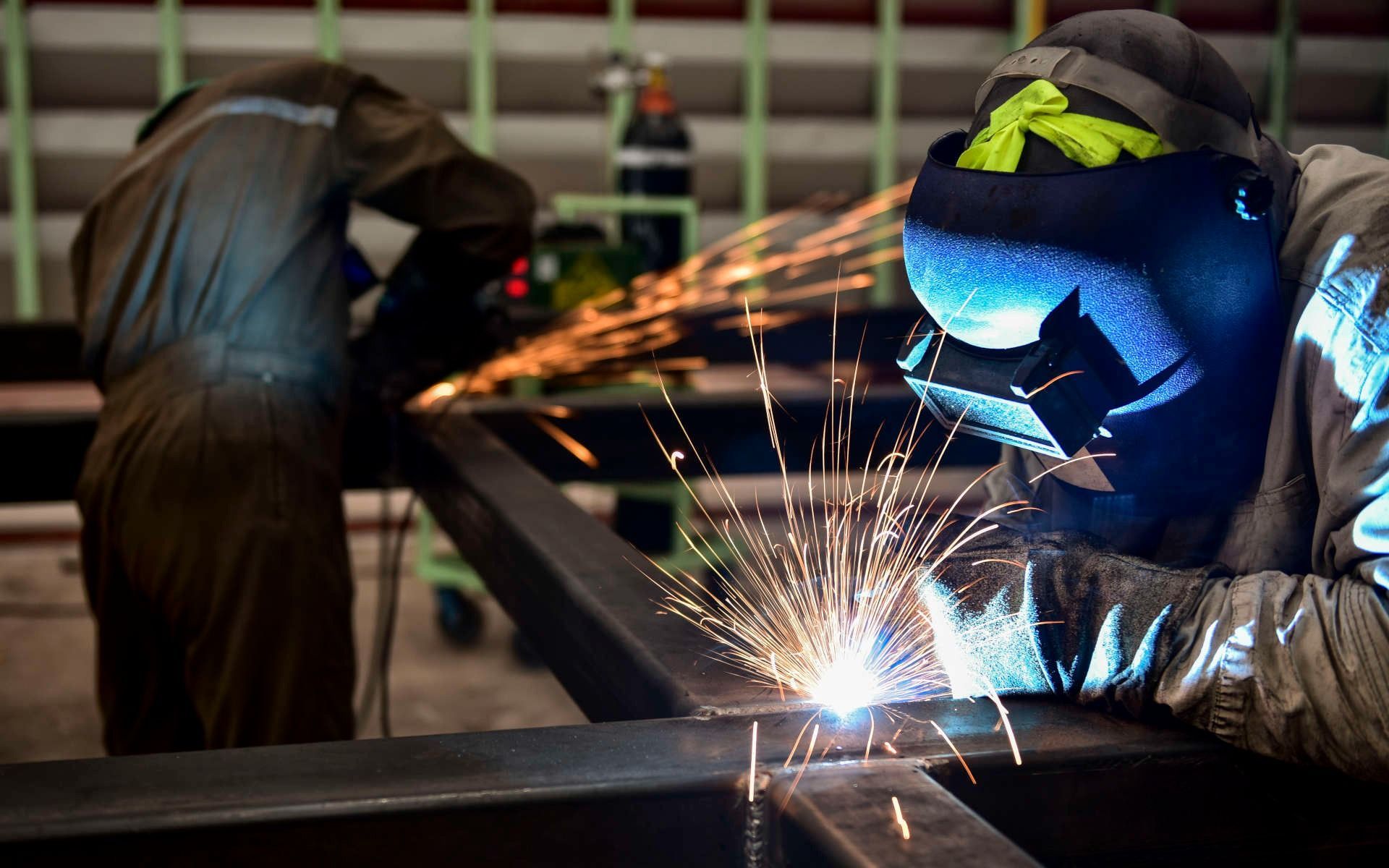Un hombre está soldando una pieza de metal en una fábrica.