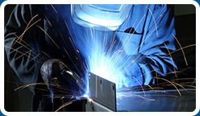 Un hombre que lleva una máscara de soldador está soldando una pieza de metal.