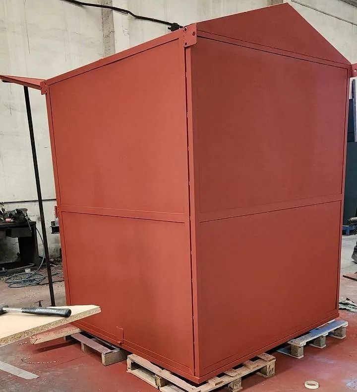 Un cobertizo rojo está situado encima de paletas de madera en un almacén.