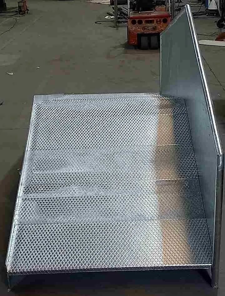 Una escalera de metal se encuentra sobre un piso de concreto al lado de una carretilla elevadora.
