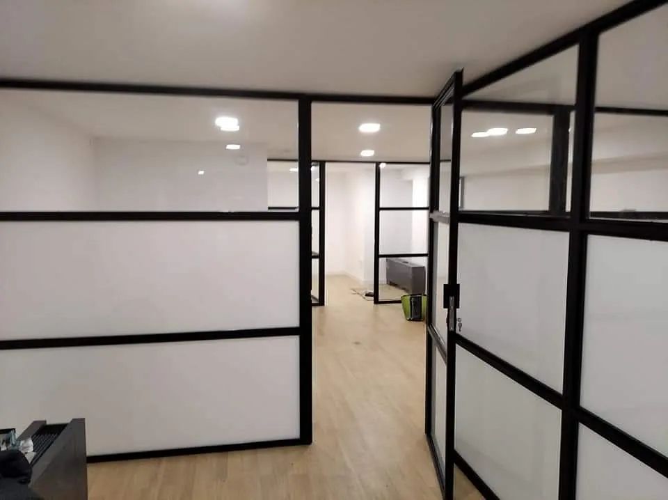 Un pasillo con muchos separadores de vidrio y piso de madera.