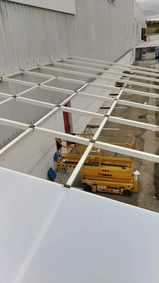 Un elevador de tijera amarillo está estacionado bajo un techo transparente.