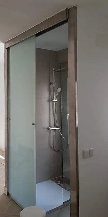 Un baño con ducha y puerta corrediza de cristal.