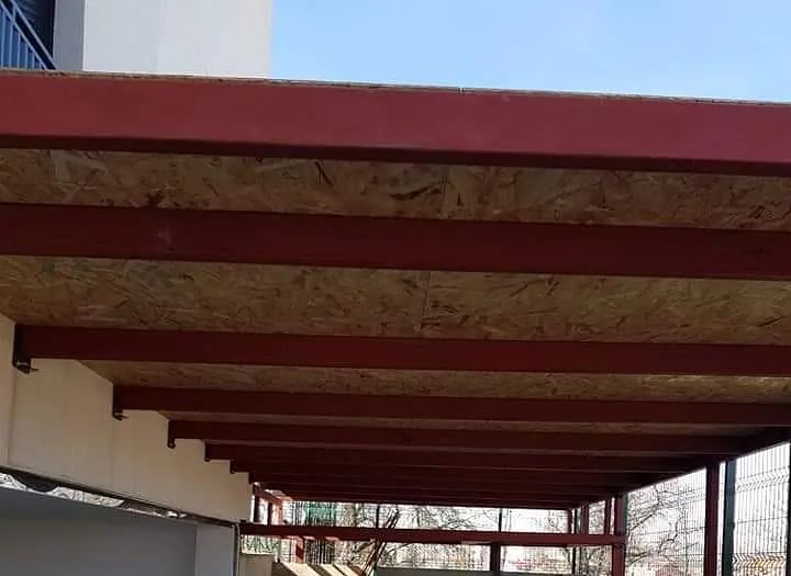 El techo de un edificio con tejado de madera contrachapada y vigas metálicas.