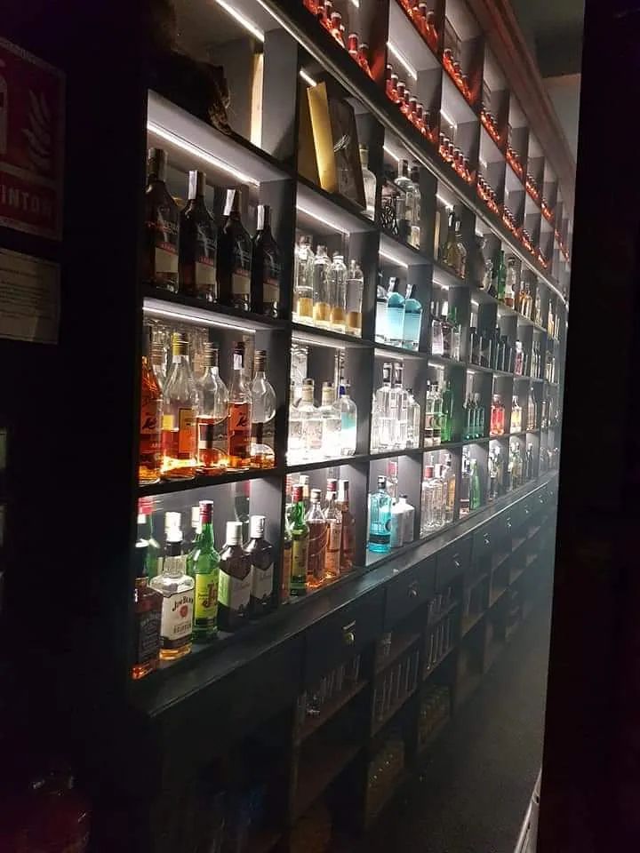 Una fila de estantes llenos de botellas de licor en una habitación oscura.