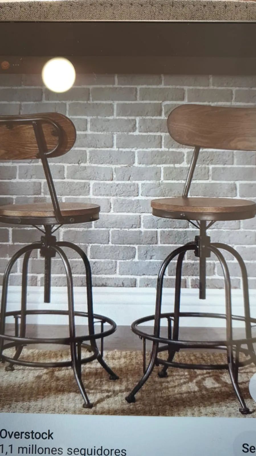 Dos taburetes de bar están sentados frente a una pared de ladrillos.