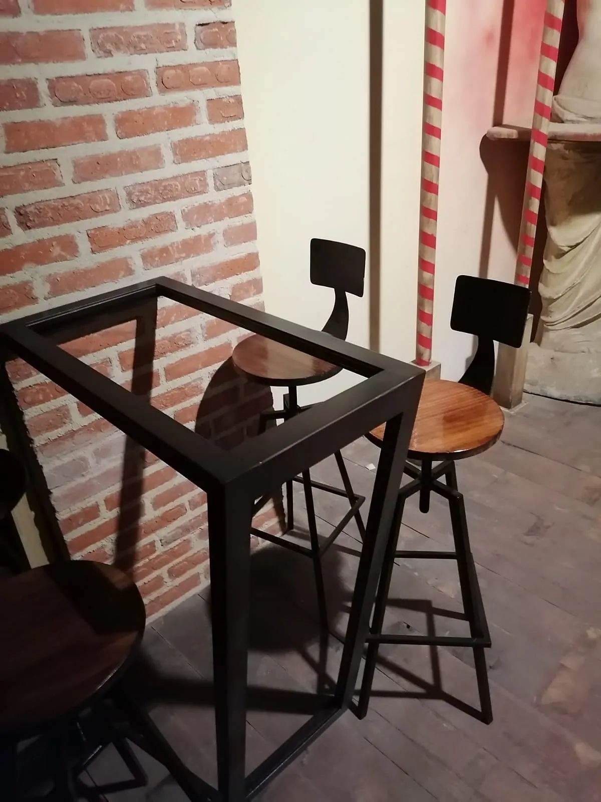 Una mesa y sillas en una habitación con una pared de ladrillos.