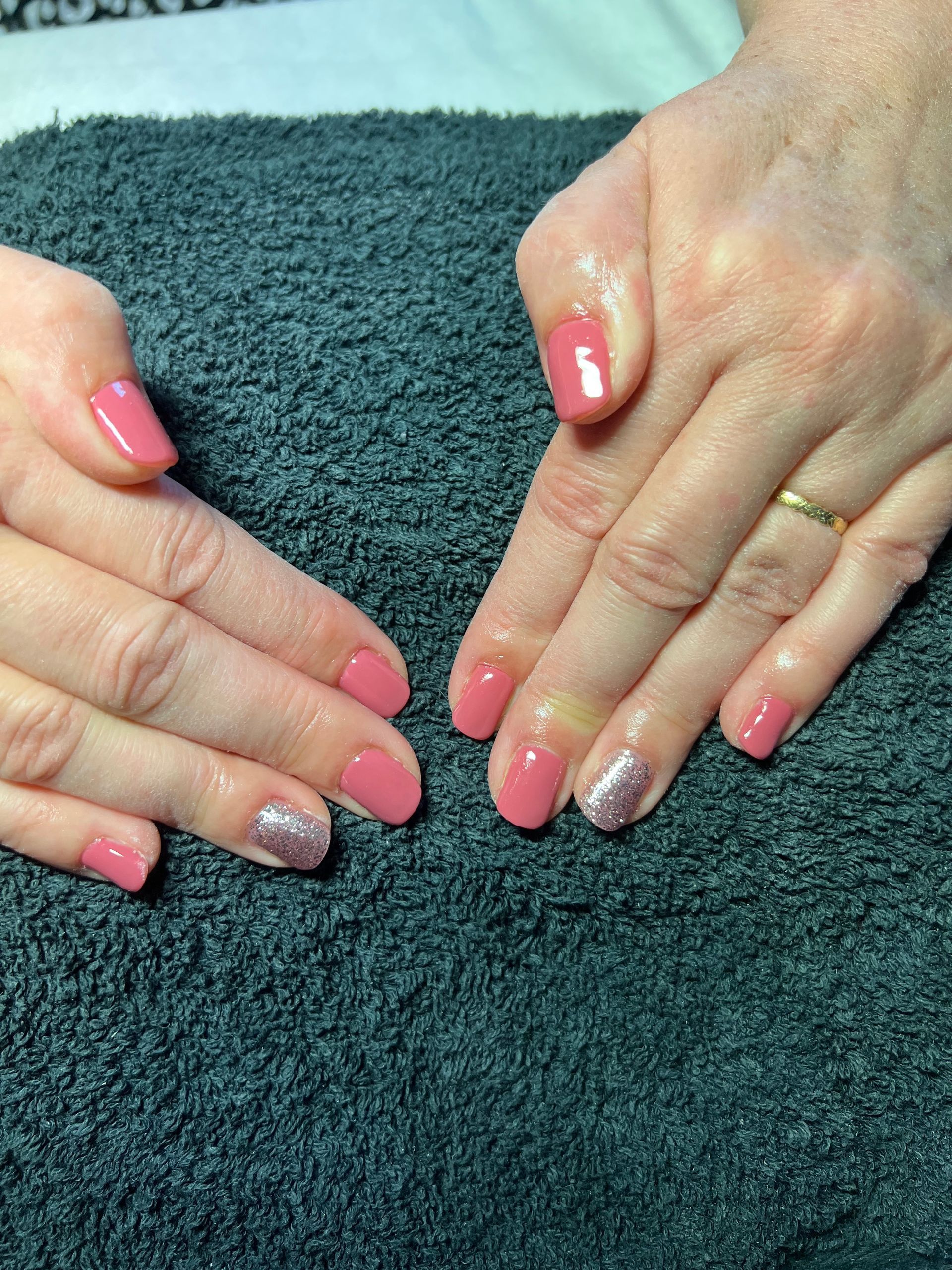 Des mains aux ongles roses manucurés reposent sur une serviette bleu sarcelle foncé.