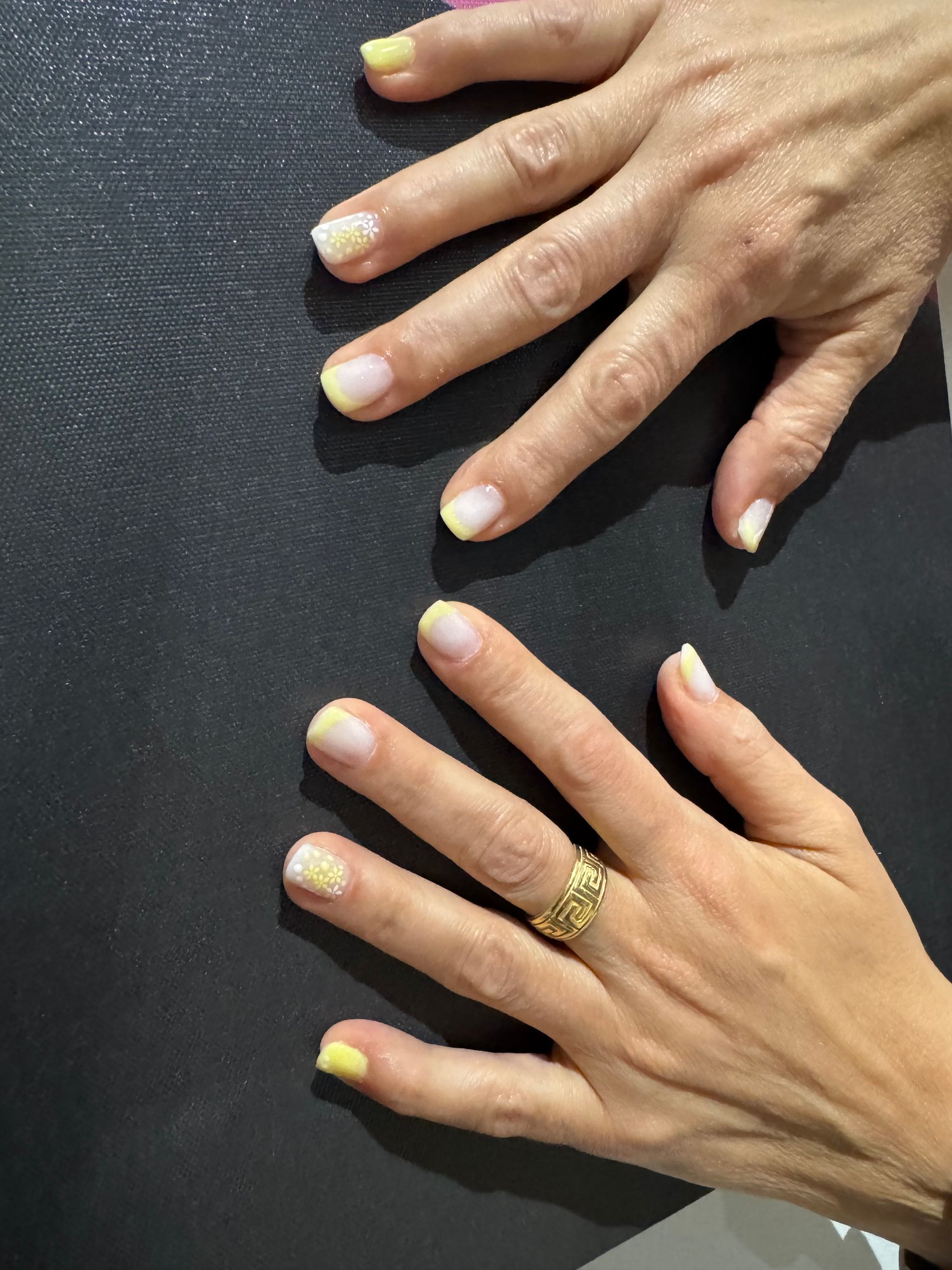Deux mains aux ongles manucurés sur une surface texturée foncée