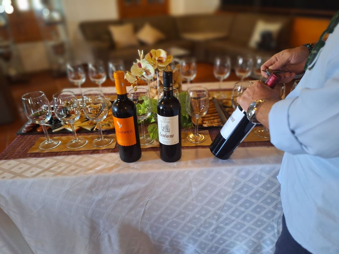 Un hombre está vertiendo una botella de vino en un vaso sobre una mesa.