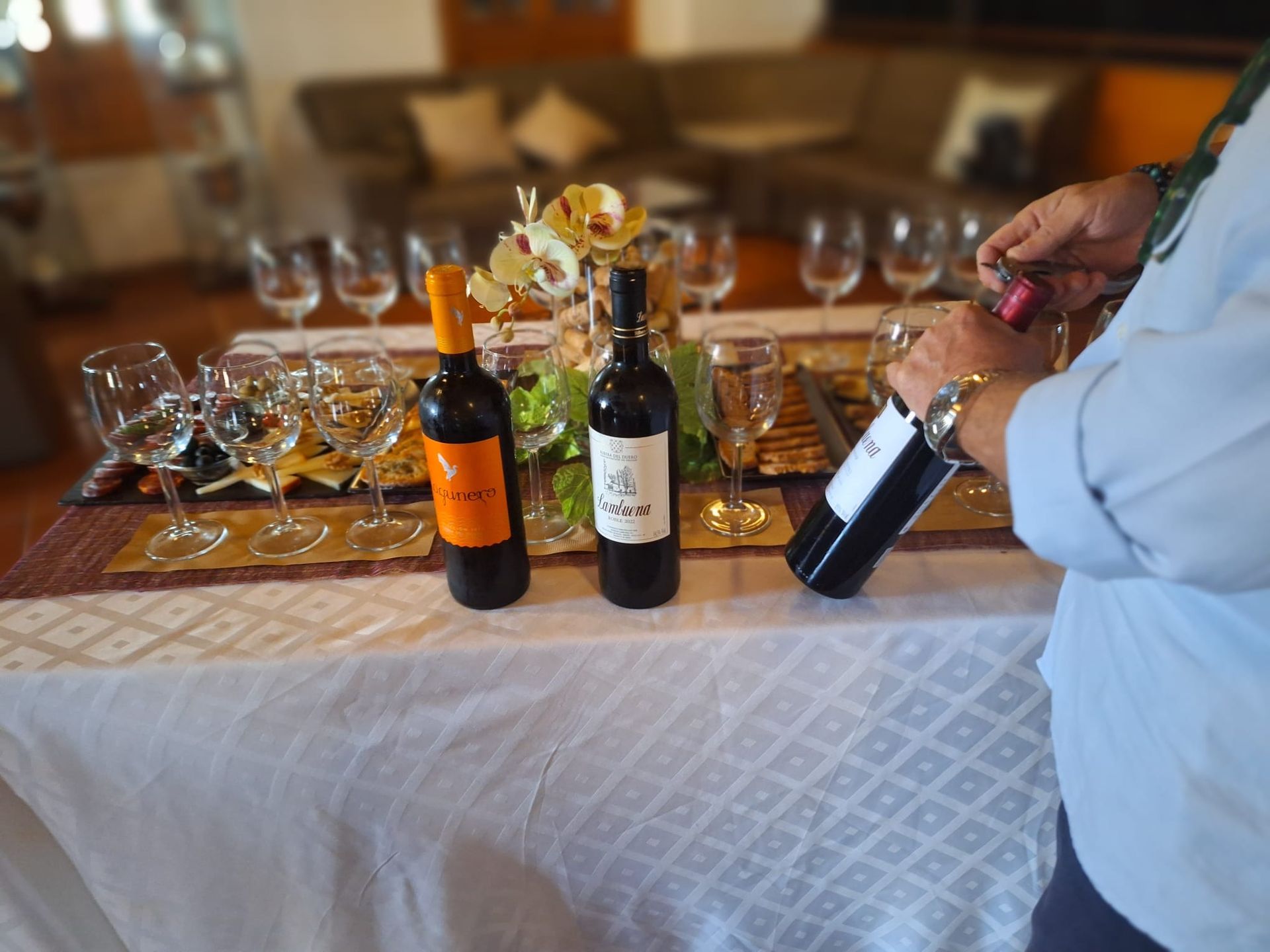 Un hombre está vertiendo una botella de vino en un vaso sobre una mesa.