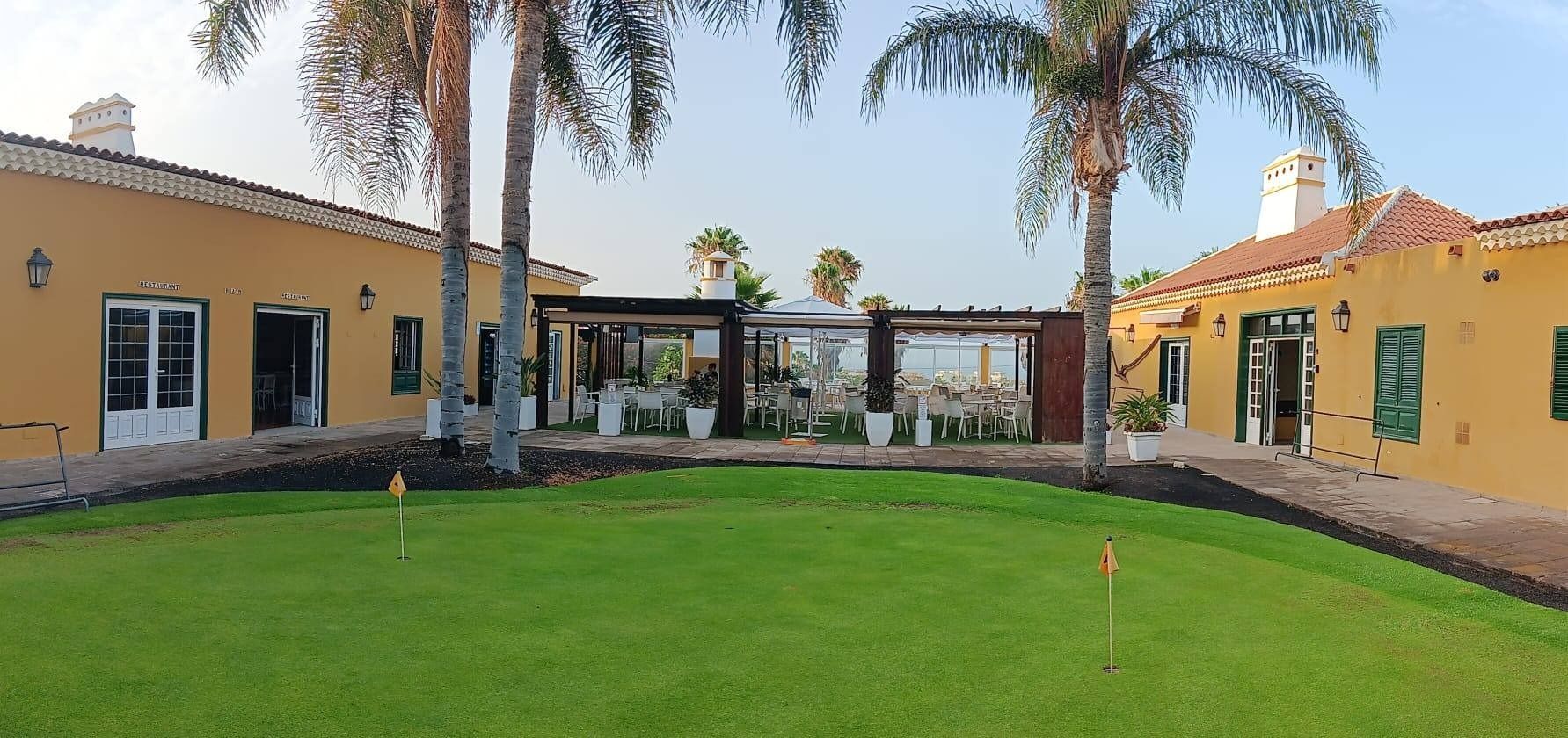 Una casa grande con un putting green en frente.