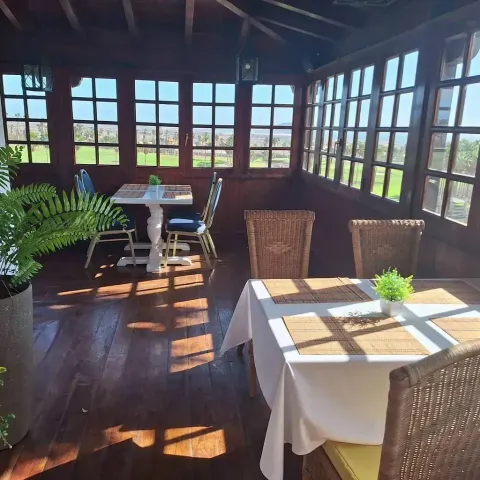 Un comedor con mesas y sillas y muchas ventanas.
