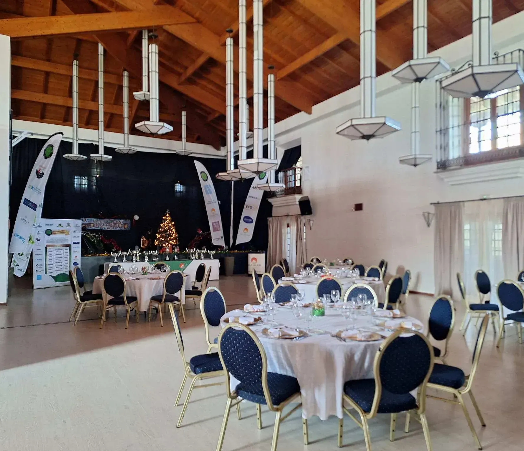 Una gran sala con mesas y sillas y un árbol de Navidad al fondo.