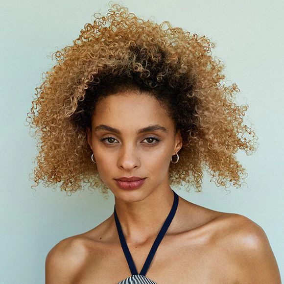 Eine Frau mit lockigem Haar trägt eine blaue Halskette