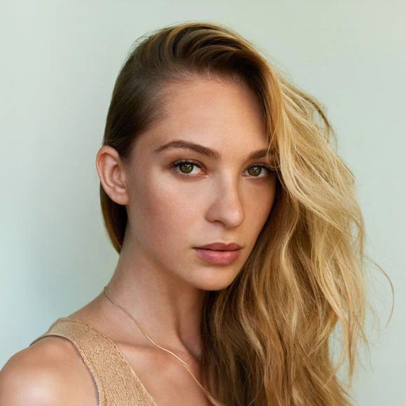 Eine Frau mit langen blonden Haaren trägt ein goldenes Tanktop