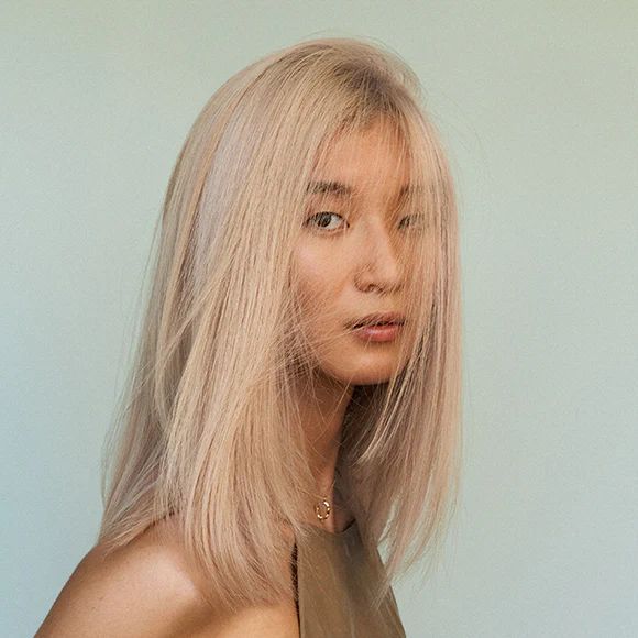 Eine Frau mit blonden Haaren steht vor einer blauen Wand.