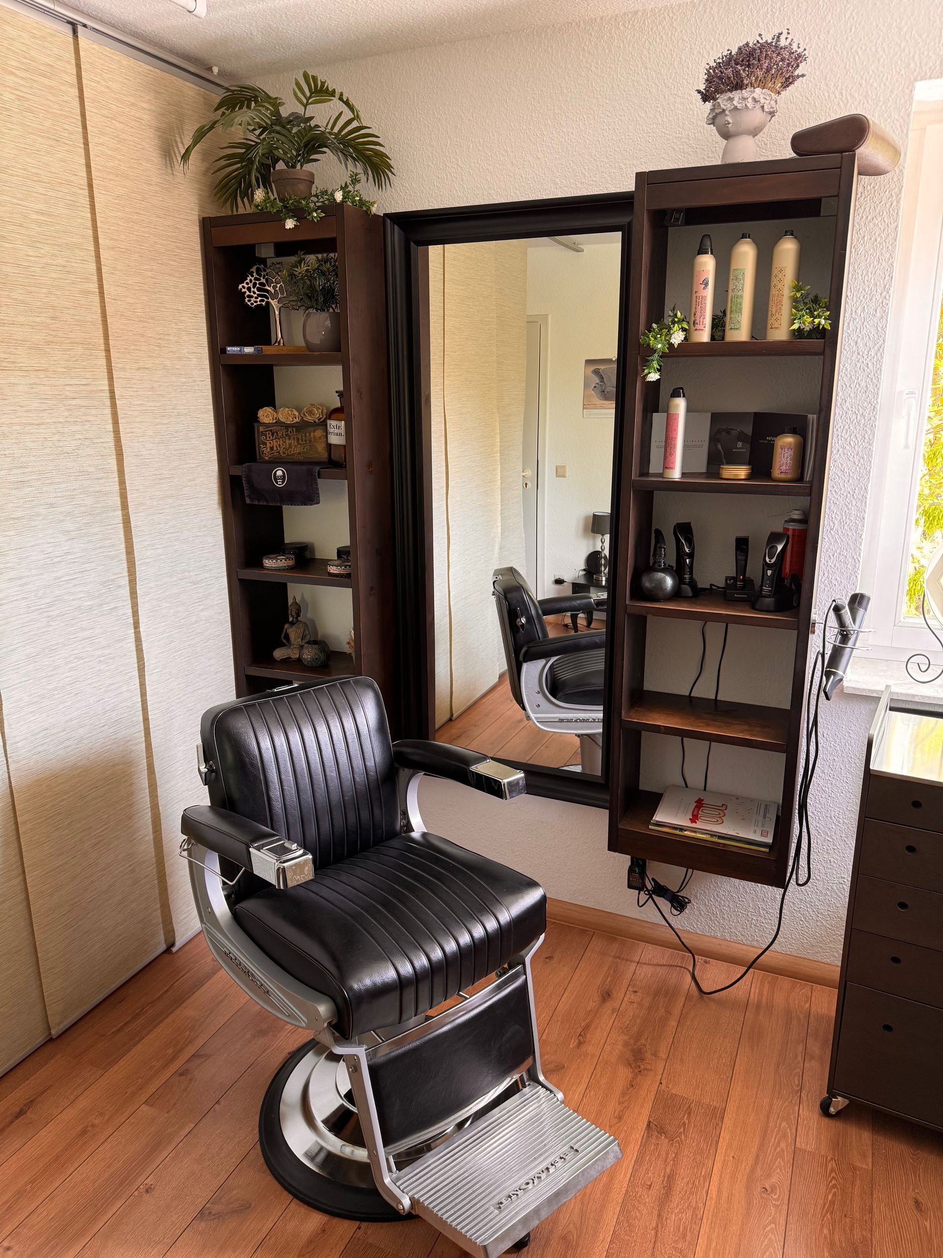 In einem Zimmer steht ein Friseurstuhl vor einem Spiegel.