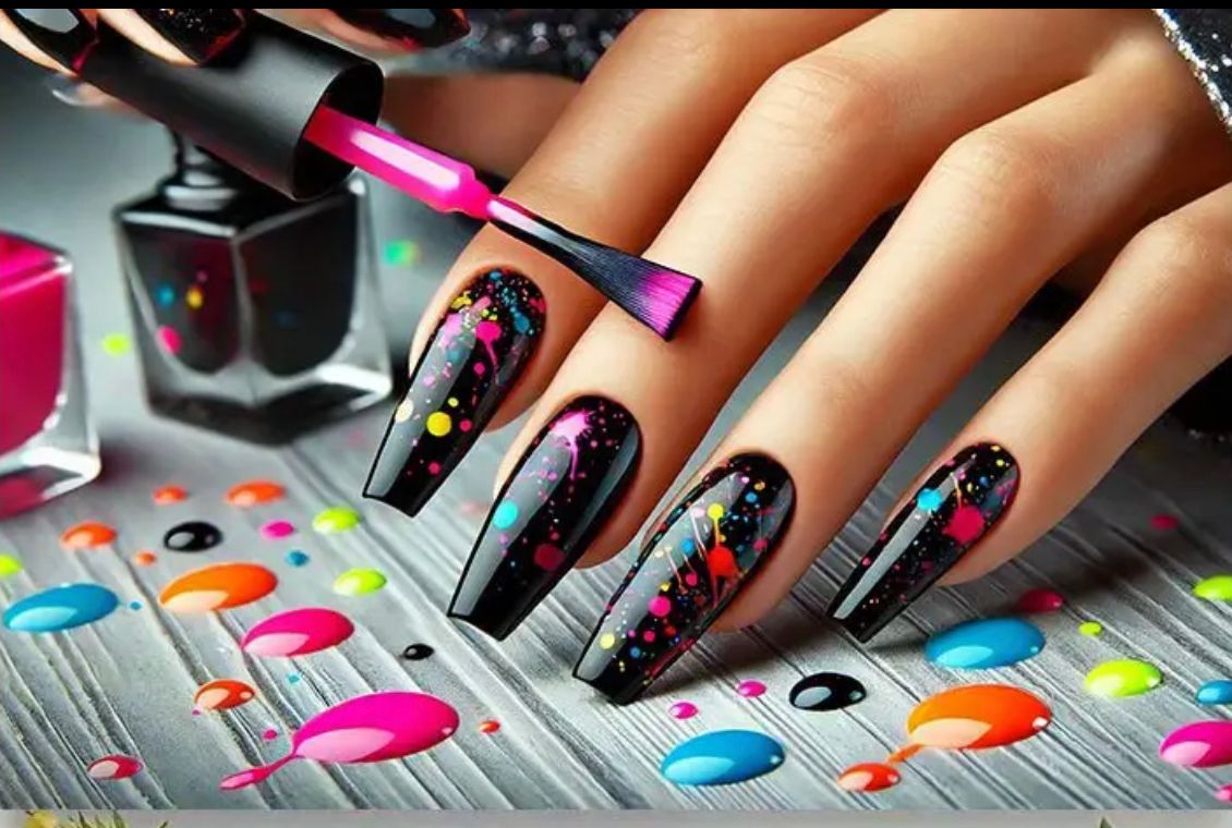 Des ongles noirs, ornés d'éclaboussures de peinture colorée, sont polis, entourés de vernis à ongles renversé.