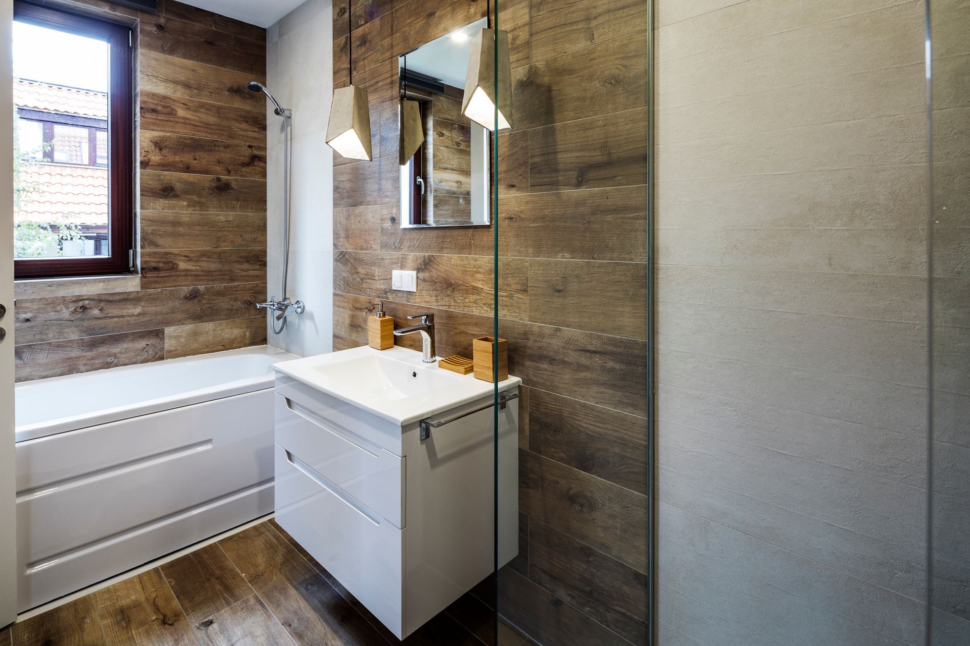 Salle de bains moderne avec des murs imitation bois, un meuble-lavabo blanc, une baignoire et une paroi de douche en verre.