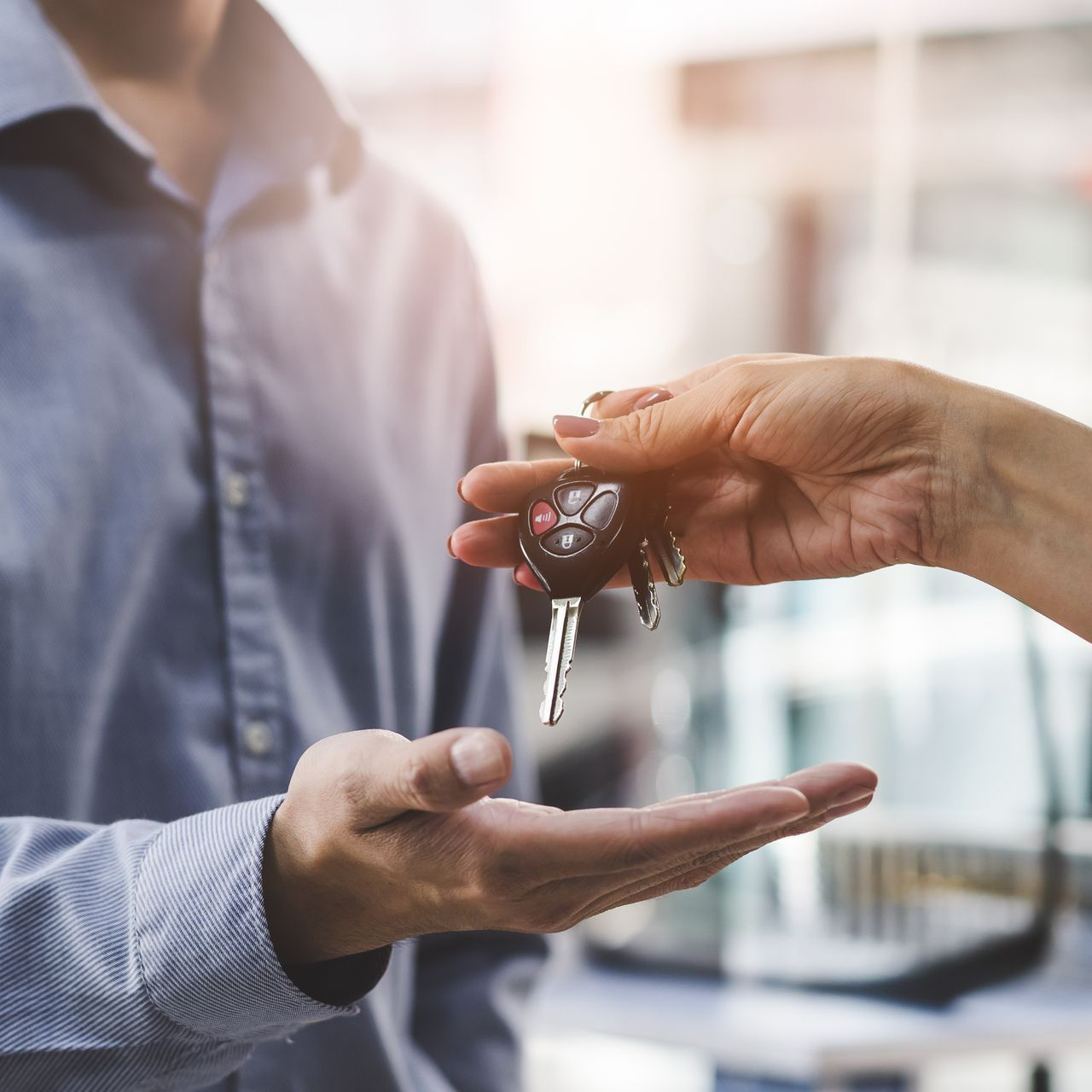 Une personne qui donne les clés de voiture à une autre personne.