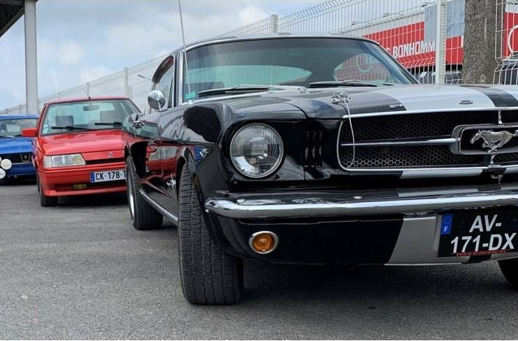 Une Mustang et une Renault garées dans un parking.