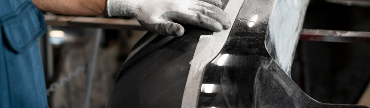 Un mécanicien en train de peindre la carrosserie d'une voiture.