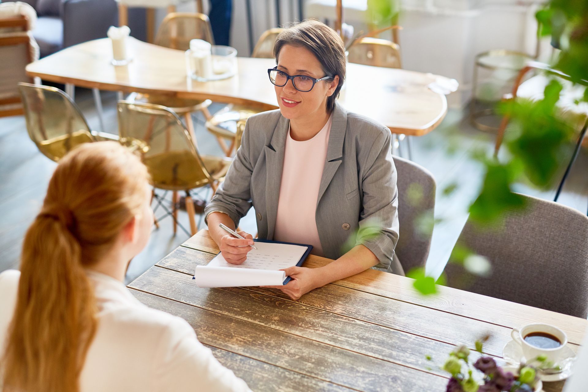 Un entretien professionnel se déroule autour d'une table en bois dans un bureau bien éclairé.