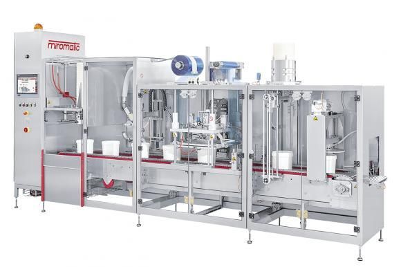 Machine d'embouteillage industrielle en acier inoxydable sur fond blanc, avec convoyeurs et panneau de commande