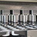 Rangée de cylindres métalliques industriels sur une machine d'usine avec des composants circulaires blancs en dessous
