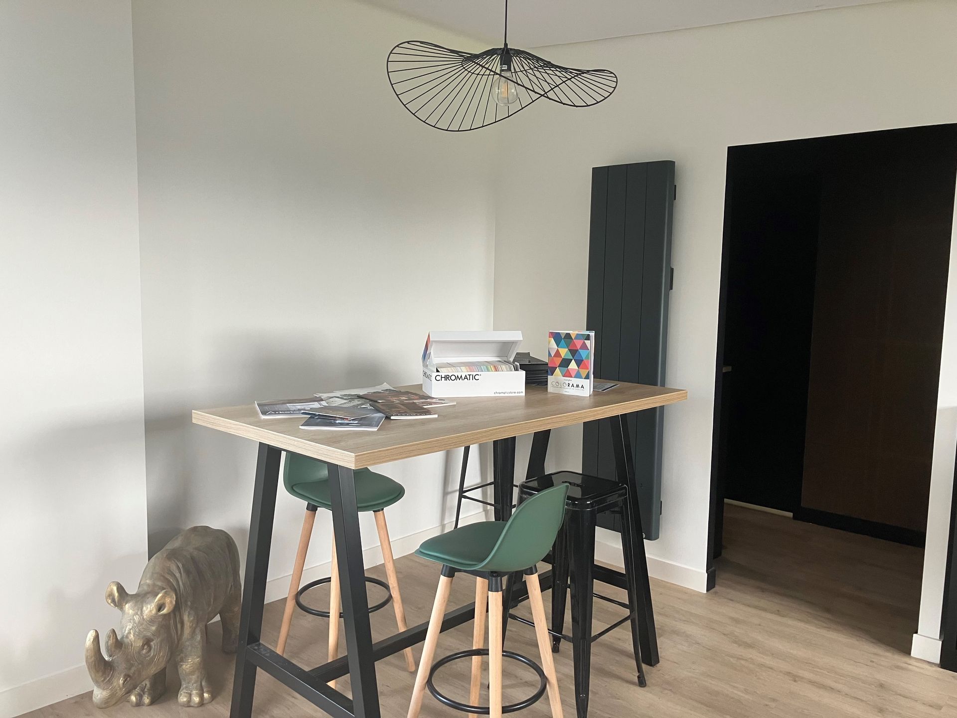 Coin moderne avec une table haute, des tabourets verts, des tableauxl.