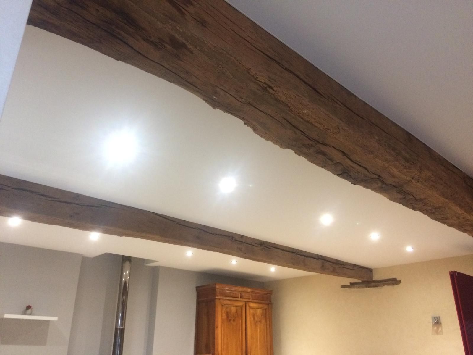 Plafond avec poutres apparentes et spots encastrés dans une pièce lumineuse