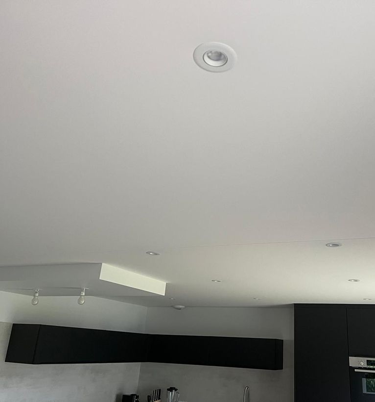 Plafond blanc minimaliste avec spots encastrés et placard mural noir dans un intérieur moderne