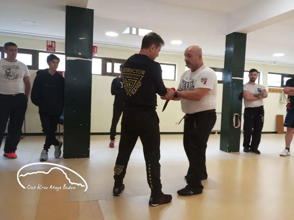 Instrucctor de defensa haciendo una demostración de ataque con cuchillo a la clase