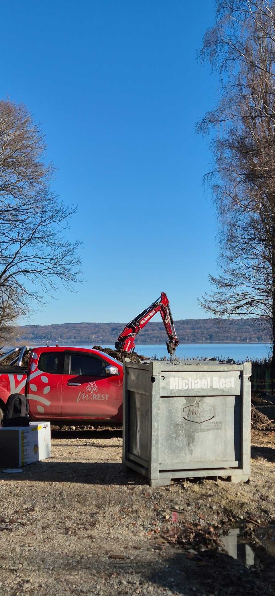 Ein roter Pickup-Truck und ein Bagger arbeiten an einem Gewässer an einem sonnigen Tag.