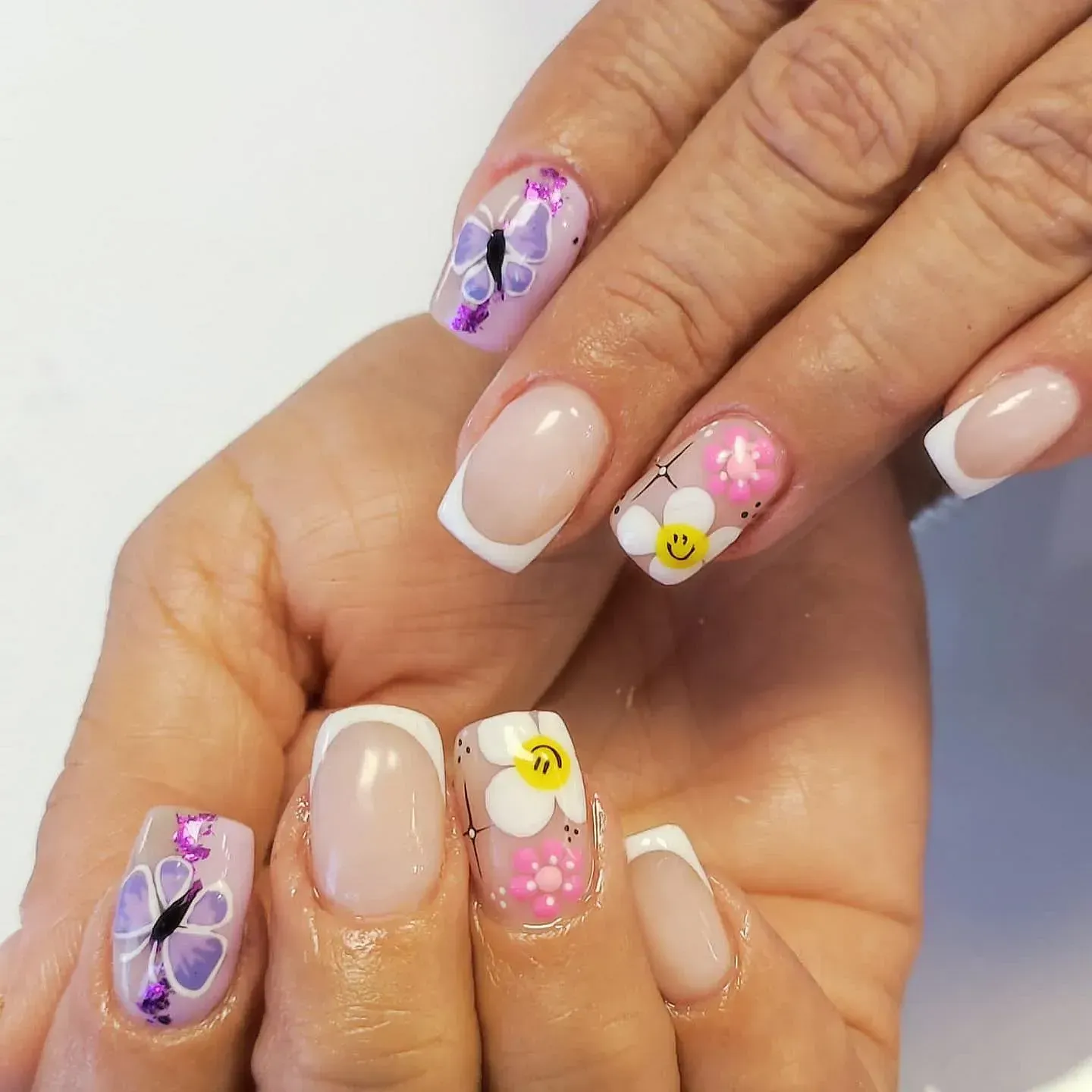 Las uñas de una mujer están decoradas con flores y mariposas.
