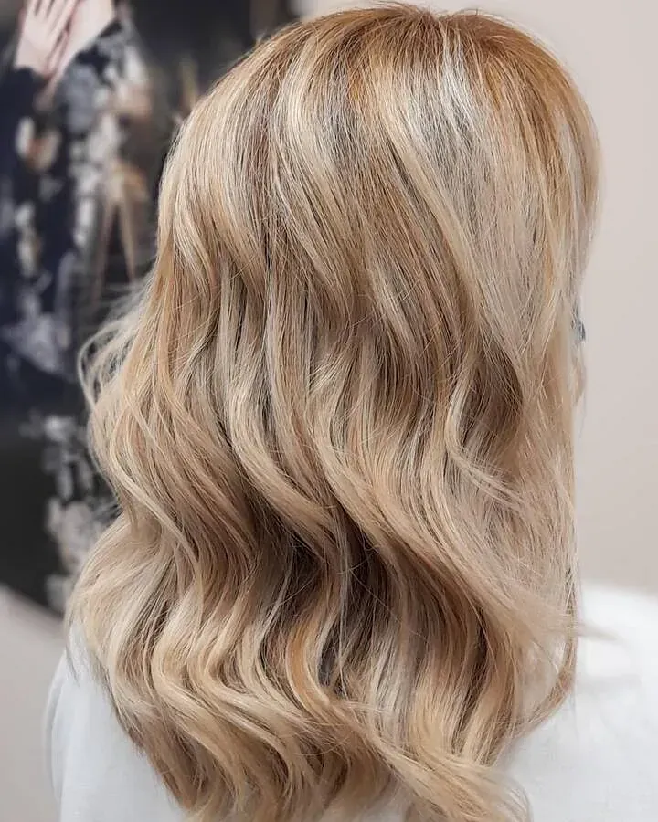 La parte posterior de la cabeza de una mujer con cabello rubio ondulado.