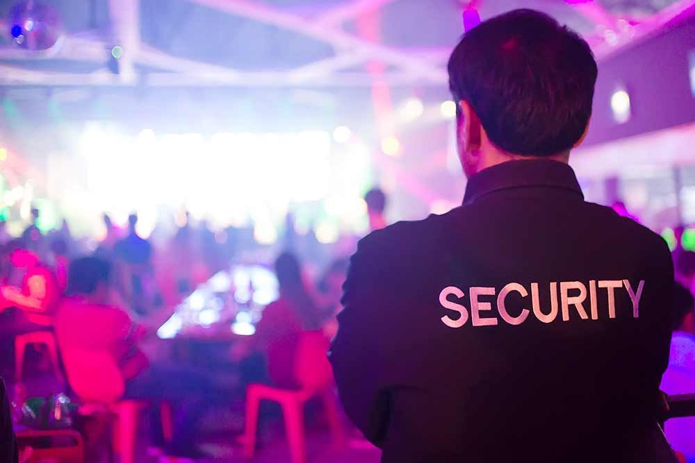 Veranstaltungssicherheit bei Großveranstaltung - ein Mann in einer Sicherheitsjacke steht in einem Club