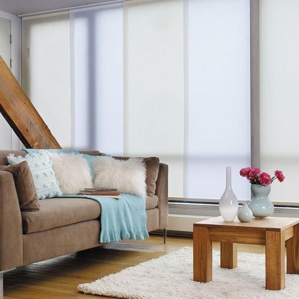 Un salon moderne avec un canapé beige, des coussins moelleux, un plaid bleu clair et une table basse en bois avec un vase de fleurs.
