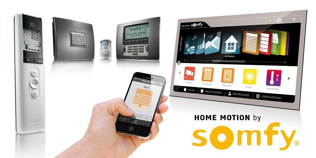 Une main tenant un smartphone affichant une interface de maison connectée, entourée d'appareils domotiques Somfy et du logo de la marque.