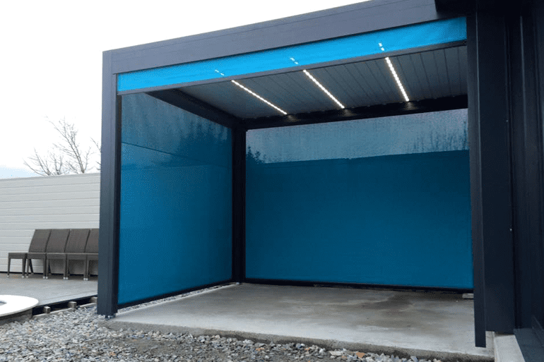 Une pergola de patio moderne à structure sombre, avec des écrans en tissu rétractables bleu vif et un éclairage intégré au plafond.
