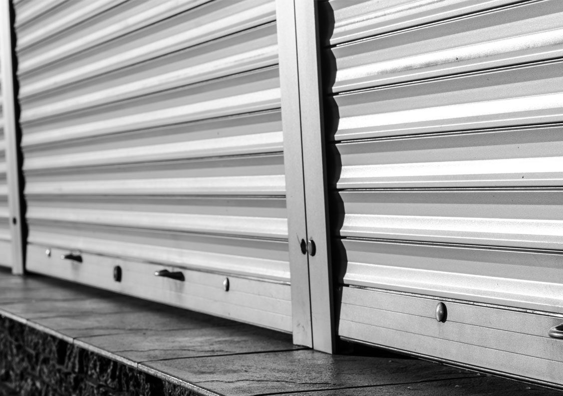 Gros plan en noir et blanc d'un bardage métallique ondulé horizontal divisé par des poutres métalliques structurelles verticales.