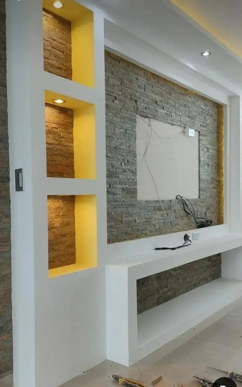 Pared moderna para la televisión, con una estantería blanca, nichos empotrados con iluminación cálida.