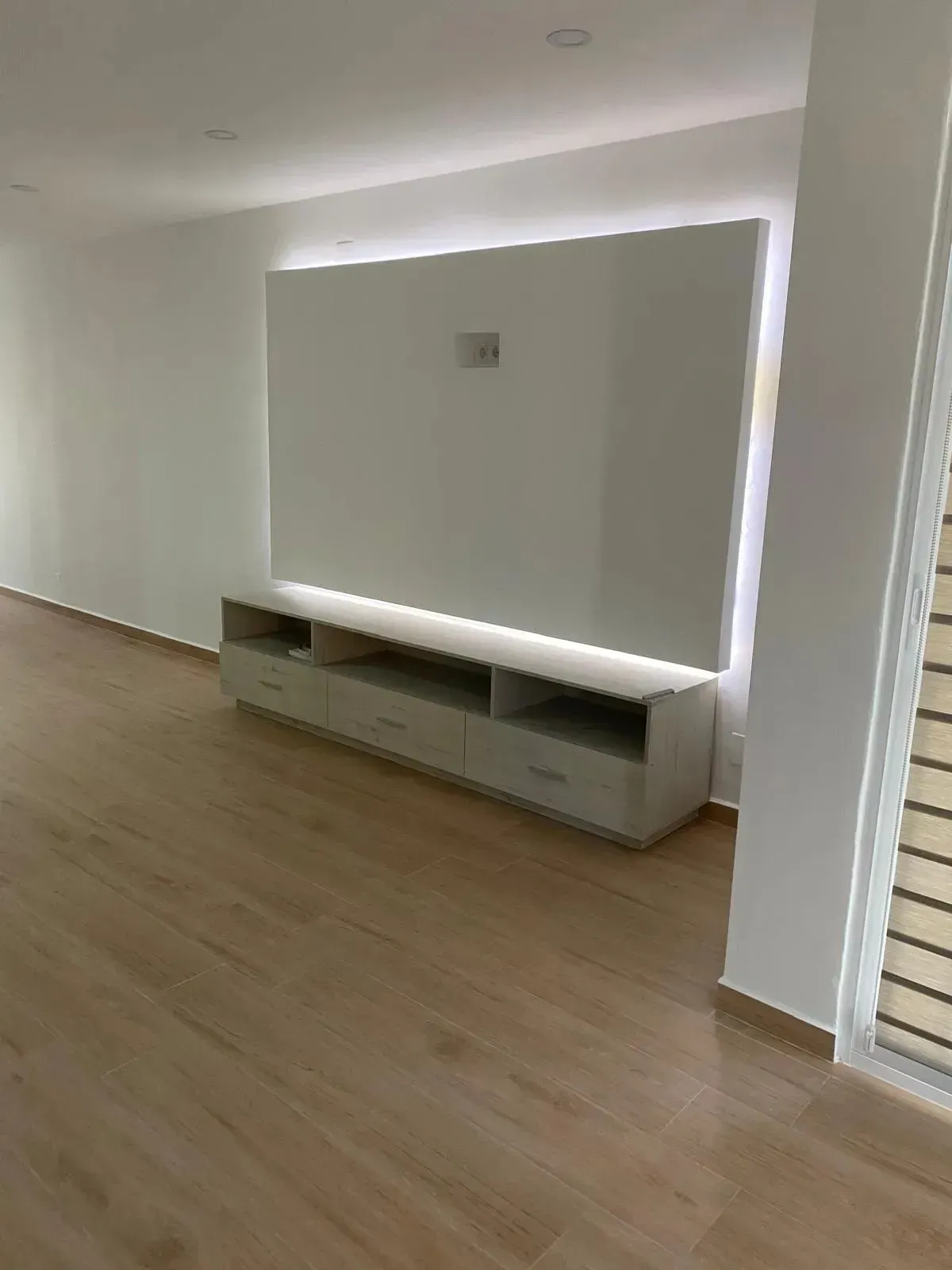 Un centro de entretenimiento flotante de color blanco, montado en la pared con una sutil iluminación LED.