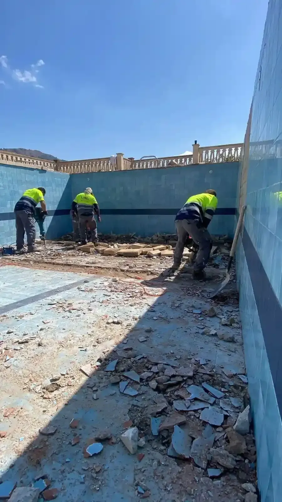 Tres obreros de la construcción, equipados con chalecos reflectantes, retiran escombros del interior .