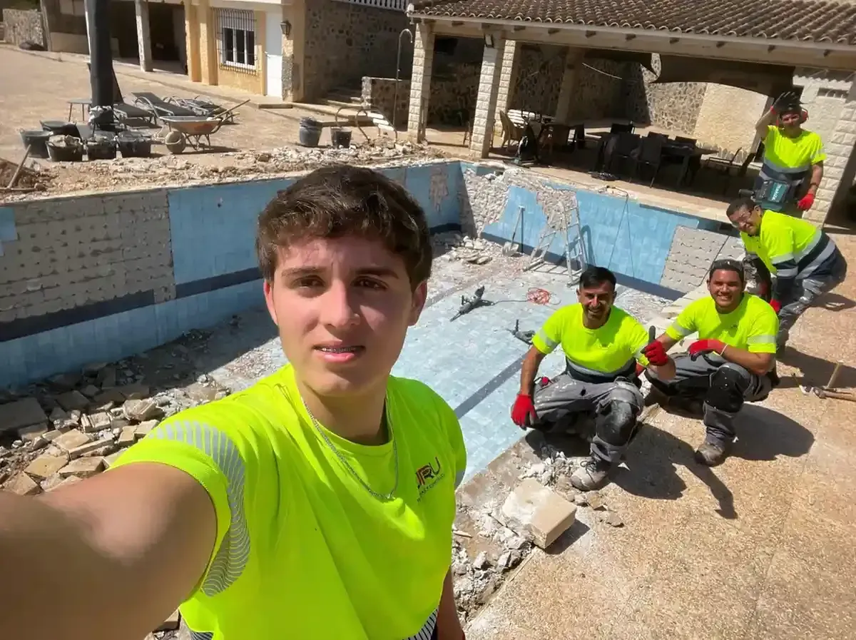 Una persona se toma una selfie con cuatro compañeros que llevan camisetas de alta visibilidad dentro de una obra.